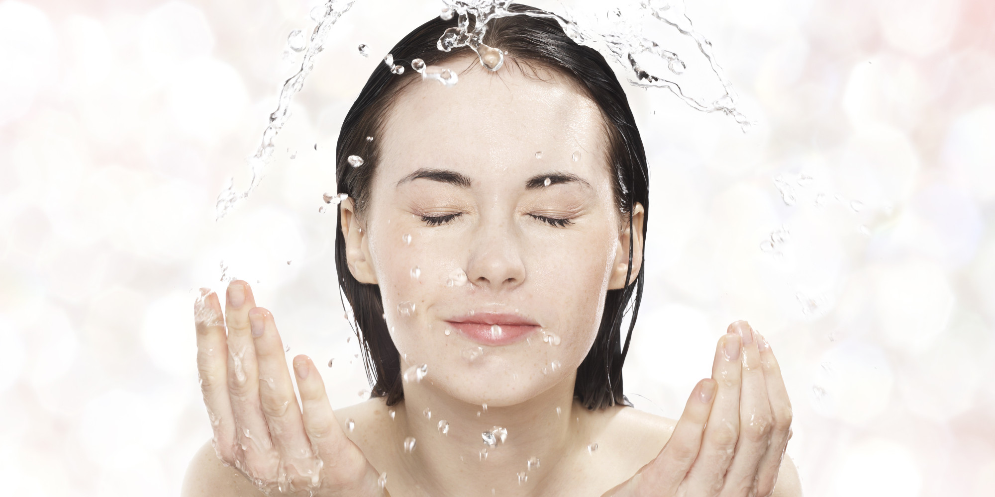 Young woman washing her face with cold water